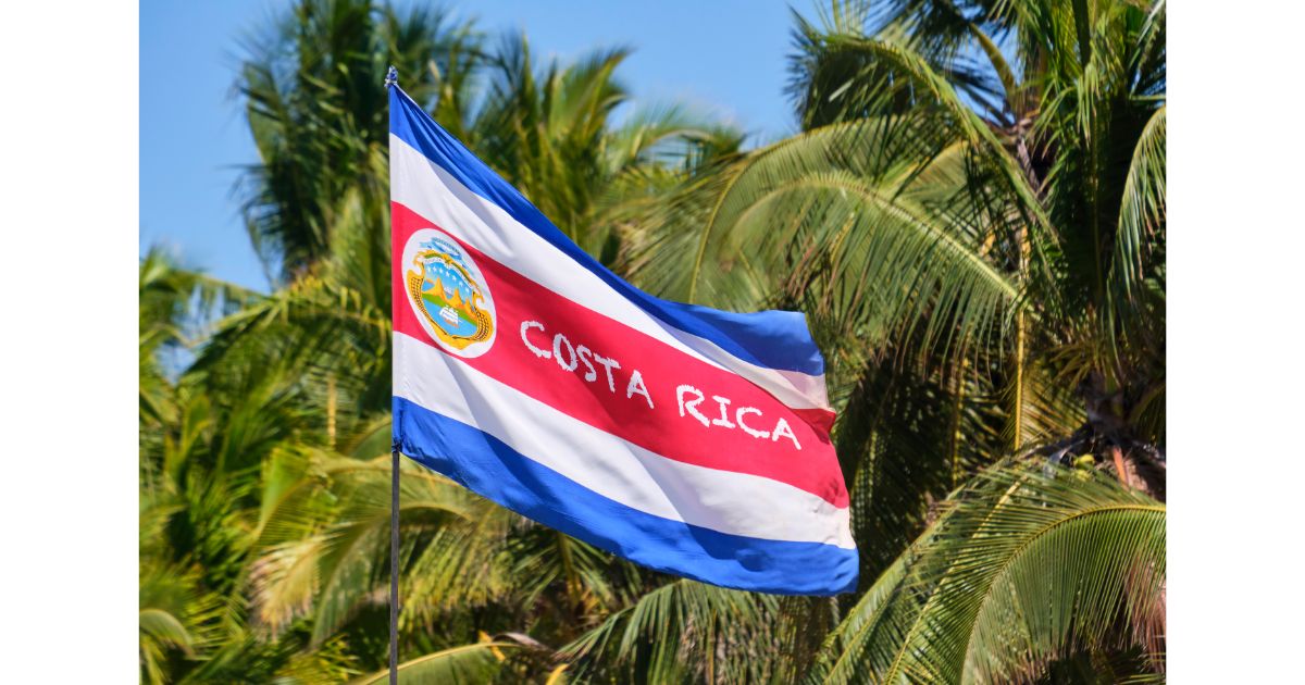 The flag of Costa Rica waving in front of palm trees, symbolizing the country's vibrant culture and natural beauty.