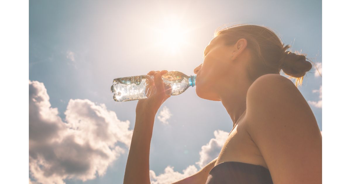 A woman drinking water under the sun