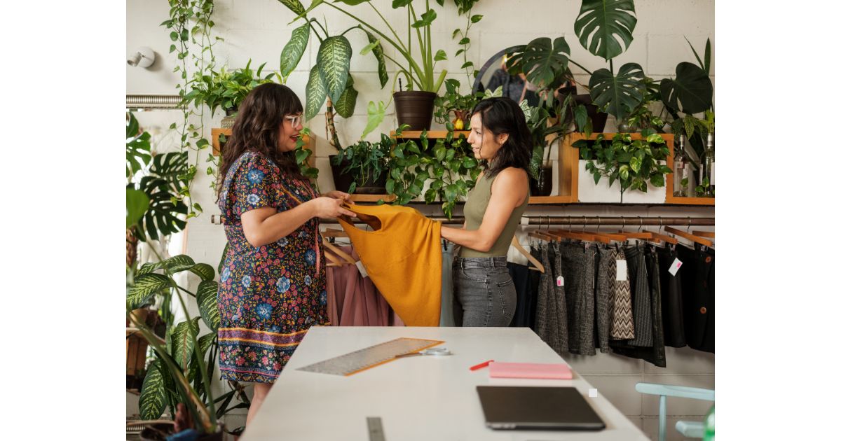 A clothing store with plants, where two women are discussing or shopping for a garment.