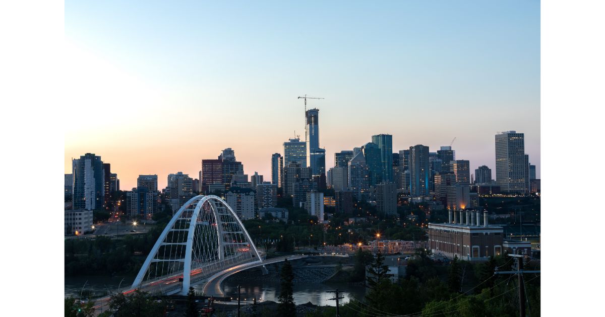 Edmonton skyline at dusk featuring the iconic Walterdale Bridge, with city buildings and a clear sky in the background.