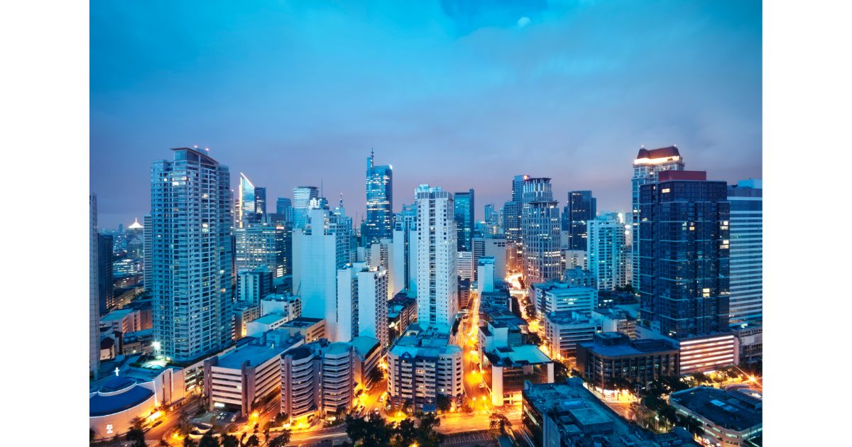 A panoramic view of the Manila skyline at dusk, showcasing modern skyscrapers and city lights.