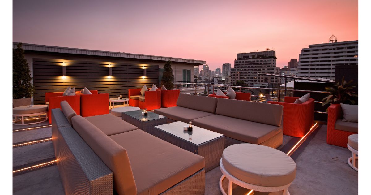 A rooftop lounge with modern seating and a stunning sunset view over the city skyline, offering a relaxed atmosphere for evening gatherings.