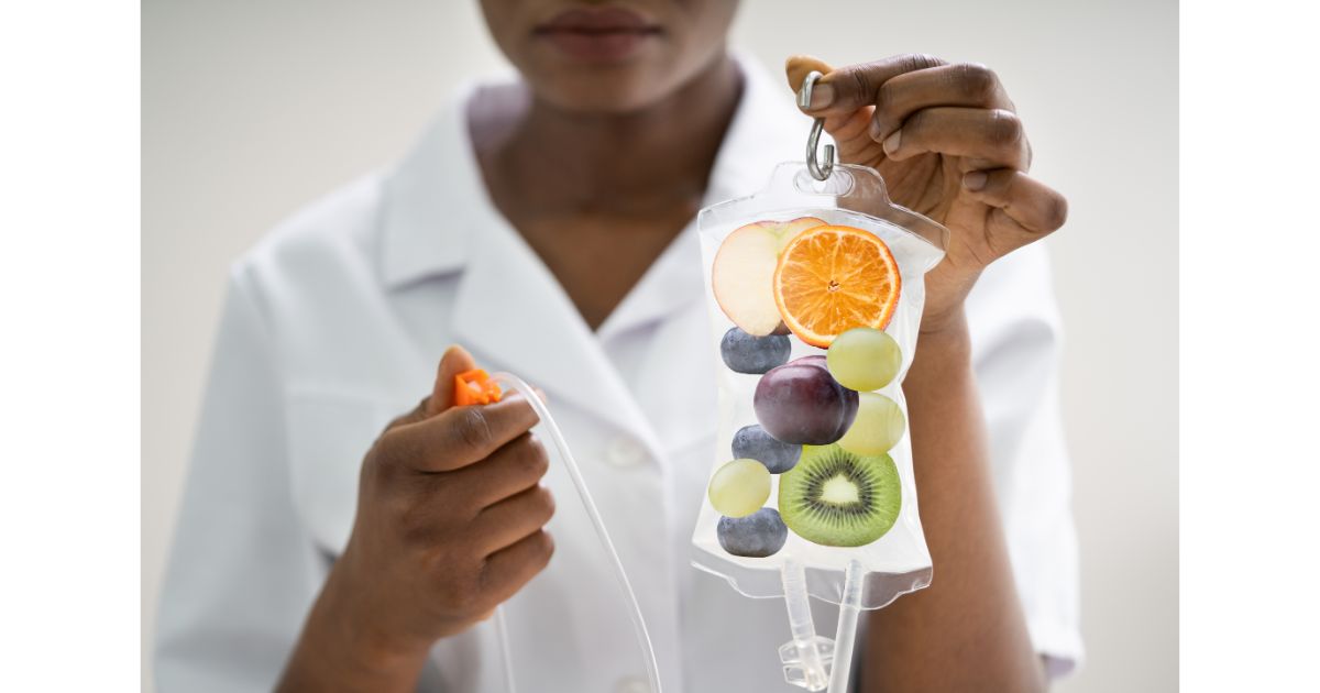 A healthcare professional holding an IV drip bag filled with fresh fruit slices, symbolizing wellness and hydration through nutrient-rich treatments.