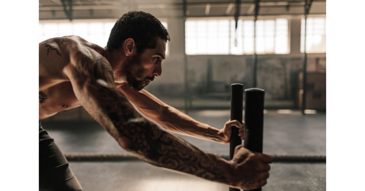 A man performing intense physical exercise using sled push equipment in a gym, focused on his workout.