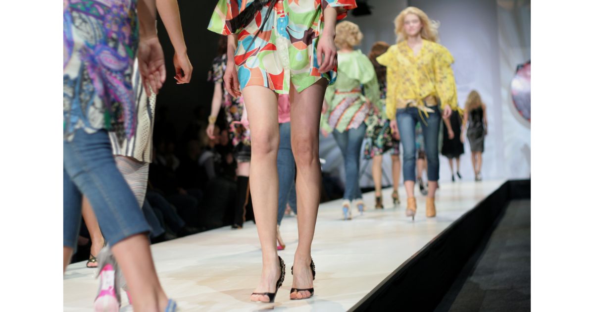 Models walking down the runway showcasing colorful fashion designs at a fashion show.