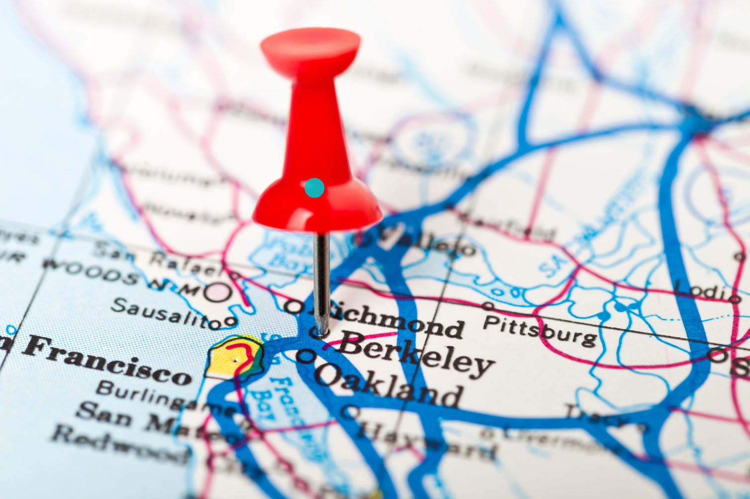 A close-up image of a map with a red pushpin marking the locations of Berkeley and Oakland in California, highlighting the surrounding areas.