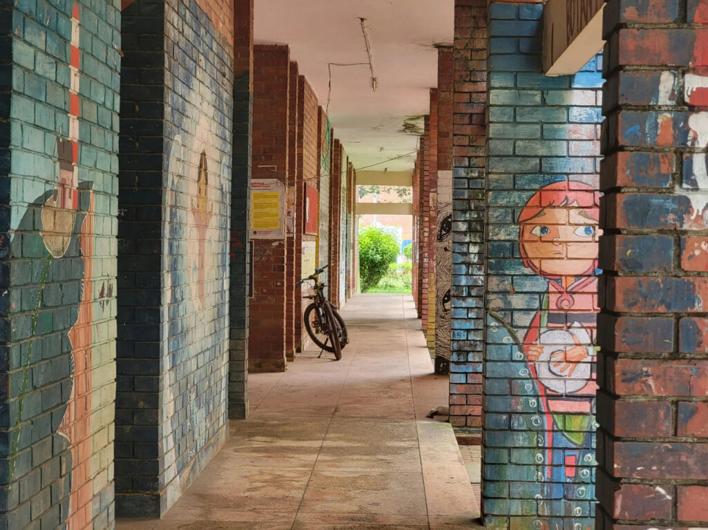 Brick-lined walkway in Santiago featuring colorful street art murals painted on columns, showcasing urban art culture and a quiet pedestrian passageway.