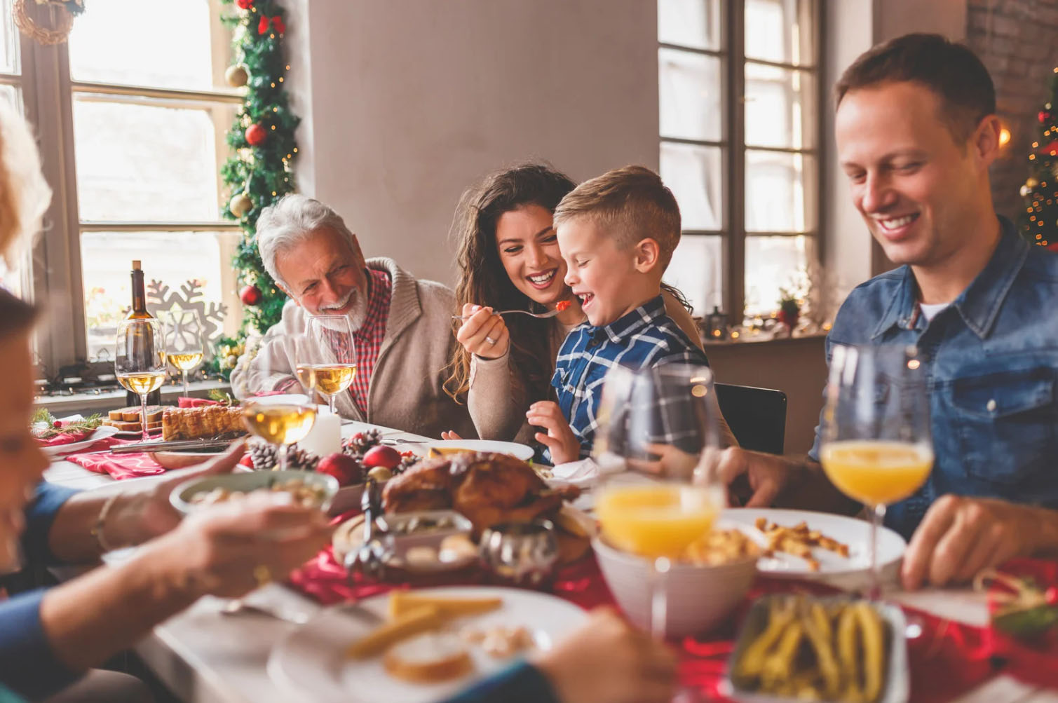 A family enjoying a festive meal together at a Christmas dinner table. The scene captures moments of joy and connection as they share food and laughter, surrounded by holiday decorations.