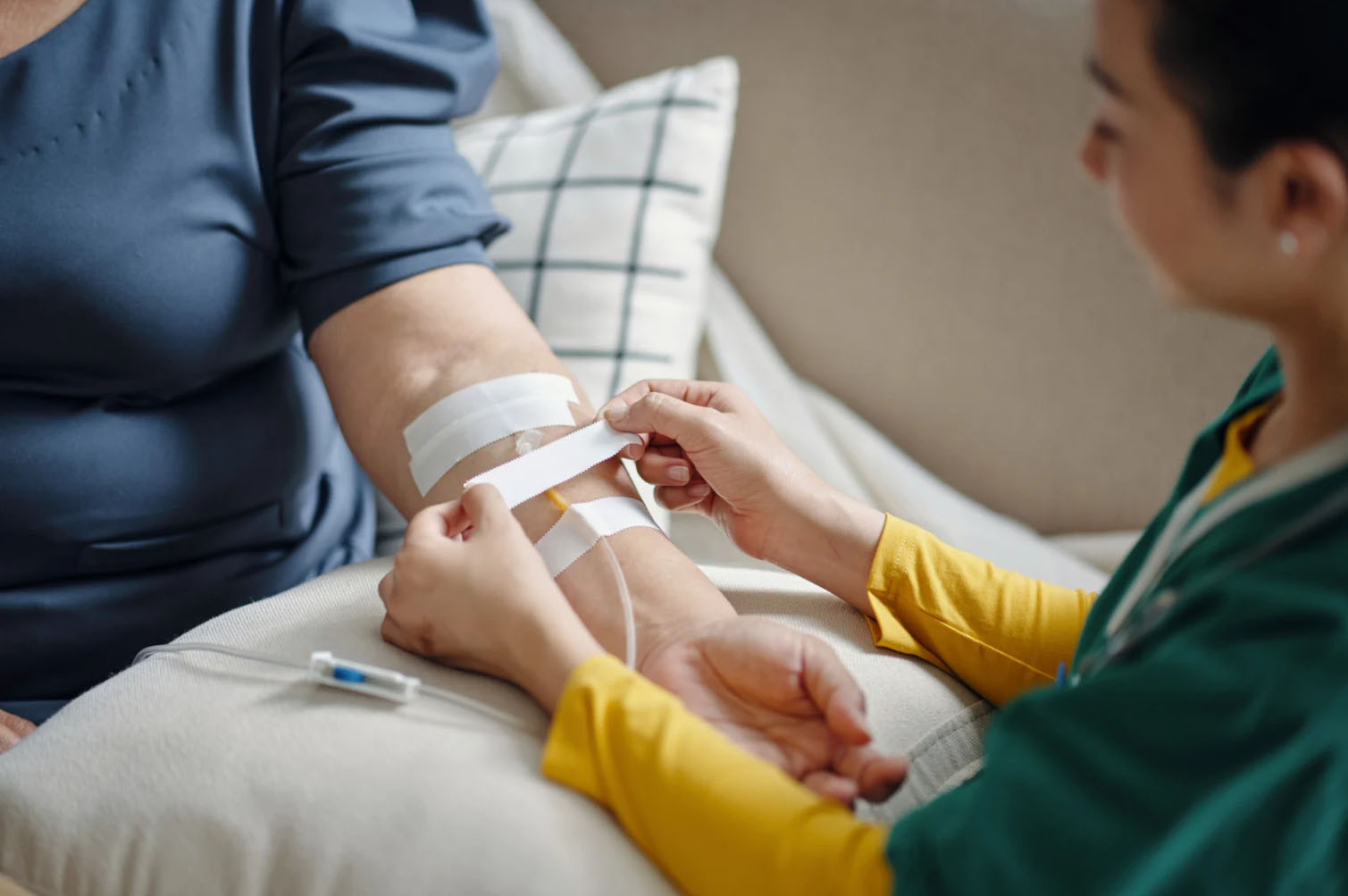A healthcare professional placing bandages on a patient's arm after administering an injection or IV therapy.