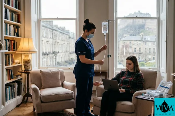 A professional registered nurse in dark blue scrubs monitors a mobile IV drip for a woman working on a laptop in a classic, high-ceilinged Edinburgh apartment. Through the large sash windows, the historic stone architecture of the city and Edinburgh Castle are visible under a soft, misty sky.
